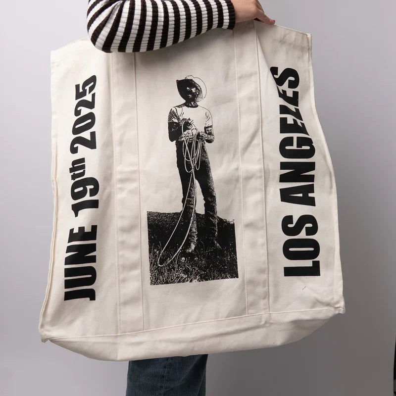 Side view of the natural canvas Post Malone LA tour tote carried over the shoulder with tour lettering